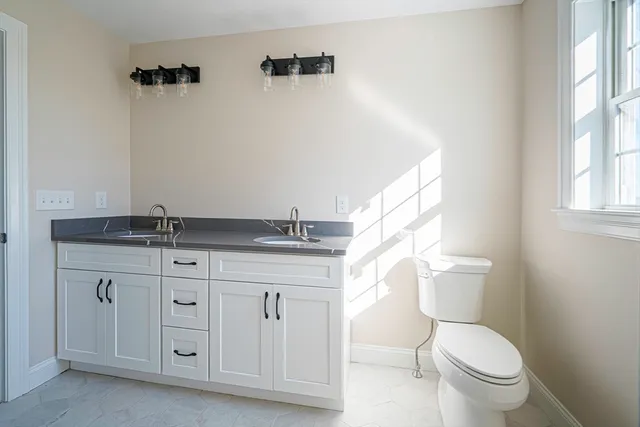a bathroom with a granite countertop toilet and a sink