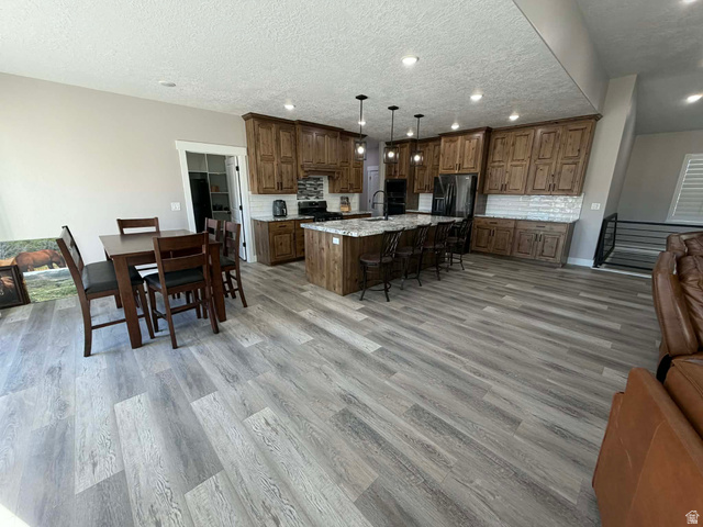 2350 North 1075 West Helper, UT 84526 - Photo 49 of 49 Kitchen with open floor plan, a breakfast bar area, an island with sink, tasteful backsplash, and a textured ceiling