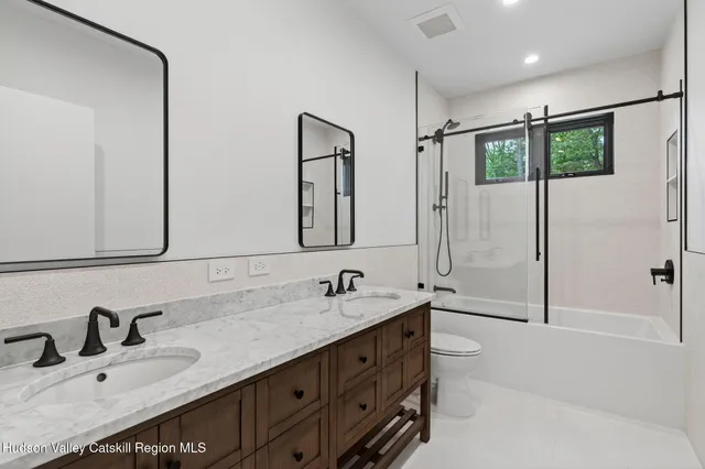 a bathroom with a double vanity sink mirror and bathtub