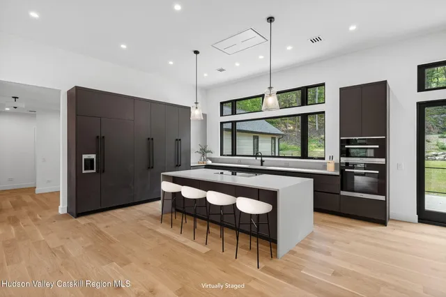 a kitchen with stainless steel appliances kitchen island granite countertop a refrigerator a oven a sink and a stove