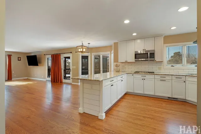 a large kitchen with stainless steel appliances granite countertop a large counter top and wooden floors
