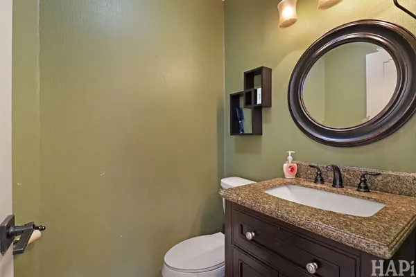 a bathroom with a granite countertop toilet sink and mirror