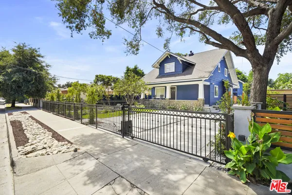 a view of a house with a small yard and large trees