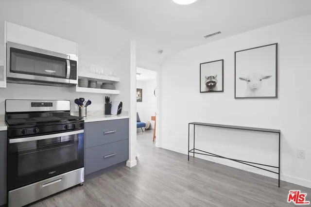 a kitchen with stainless steel appliances a stove and white cabinets