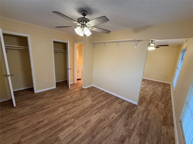 an empty room with wooden floor and a ceiling fan