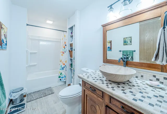 a bathroom with a granite countertop sink a toilet a mirror and shower