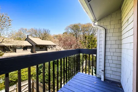 a balcony with wooden floor table and chairs