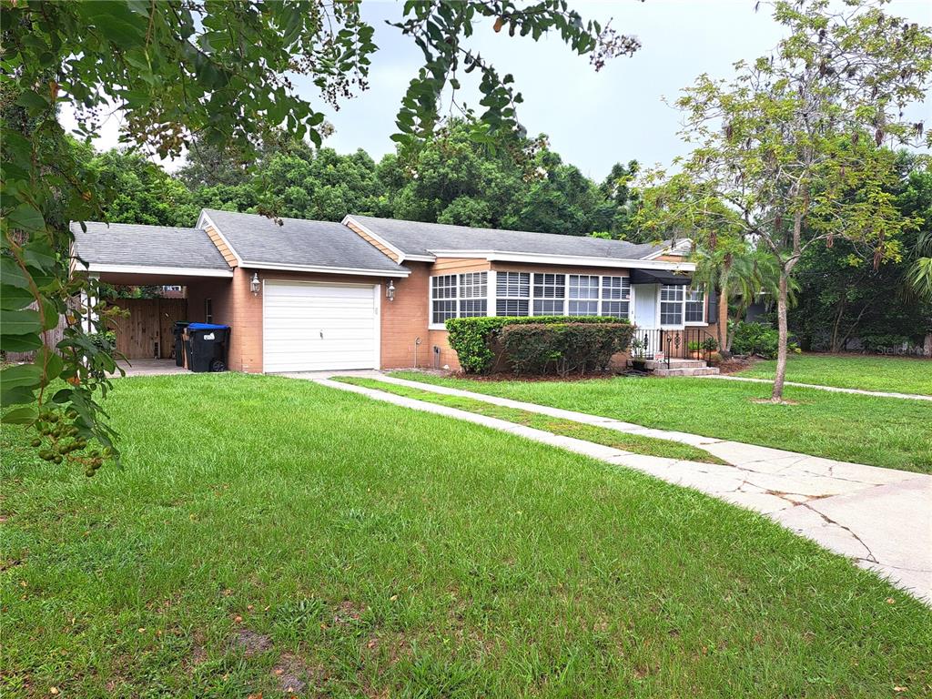 a view of a house next to a big yard and large trees