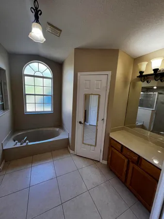 a spacious bathroom with a tub sink and mirror