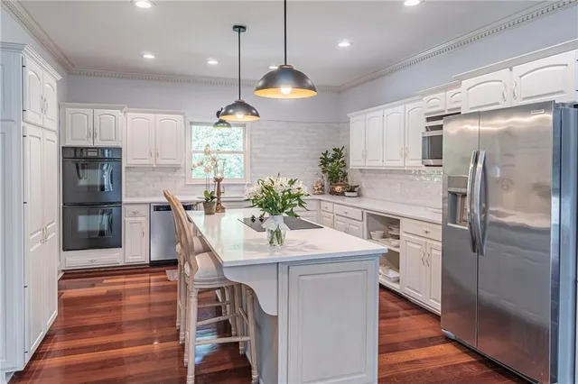 a kitchen with kitchen island granite countertop a stove a sink a oven and dining table with wooden floor