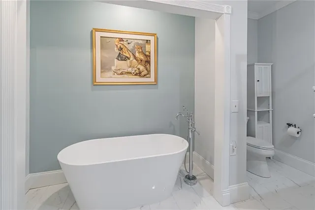 a spacious bedroom with a bed a chandelier and dresser