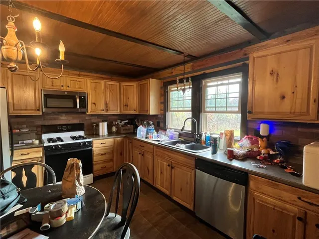 a kitchen with stainless steel appliances wooden cabinets a stove top oven a sink and dishwasher