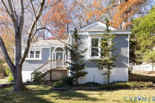 a front view of a house with a yard and large tree