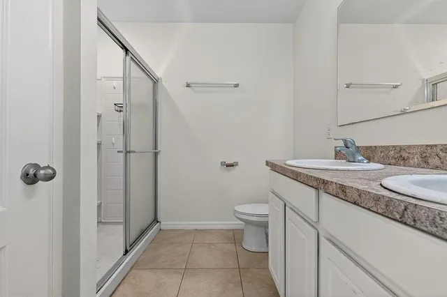 a bathroom with a granite countertop sink a toilet and shower