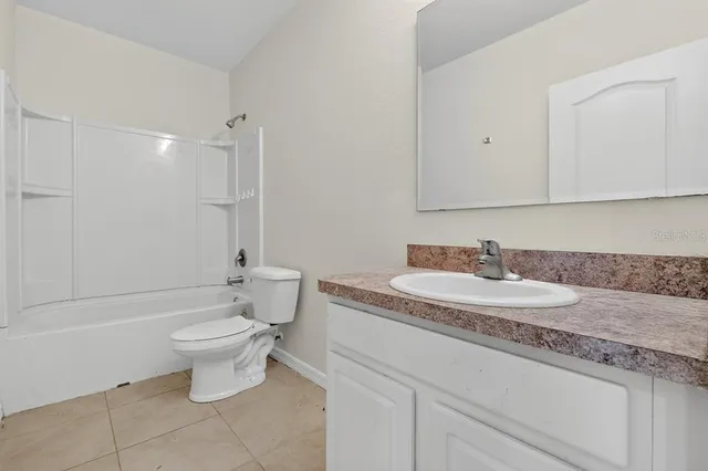 a bathroom with a granite countertop sink a toilet a mirror and bathtub