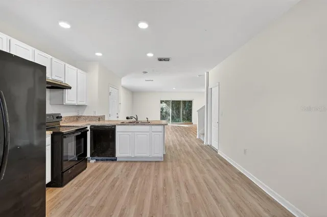 a large kitchen with a center island wooden floor stainless steel appliances and cabinets