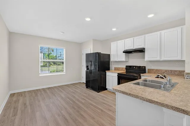 a kitchen with a refrigerator a sink a stove a microwave and wooden cabinets