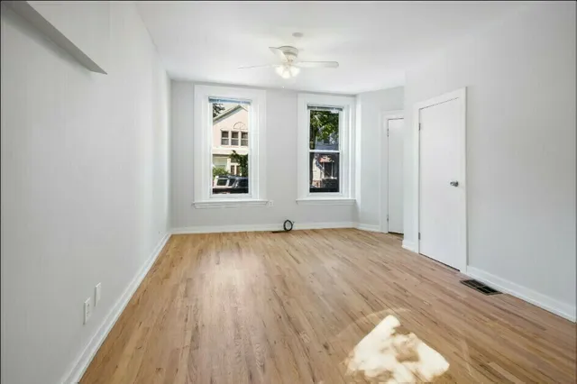 an empty room with wooden floor and windows