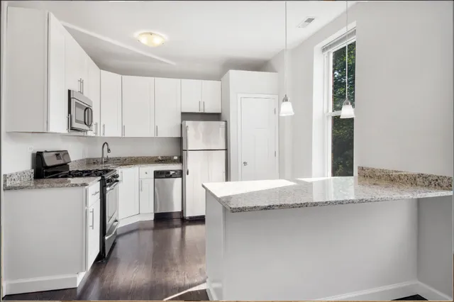 a kitchen with stainless steel appliances granite countertop a refrigerator a stove and a sink