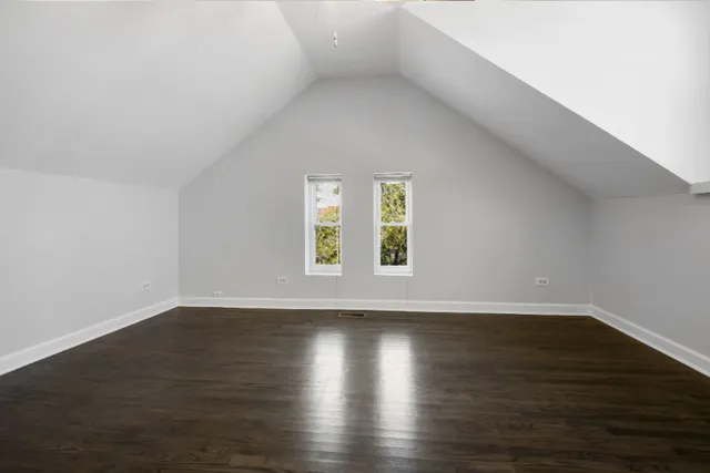 a view of an empty room with wooden floor and window