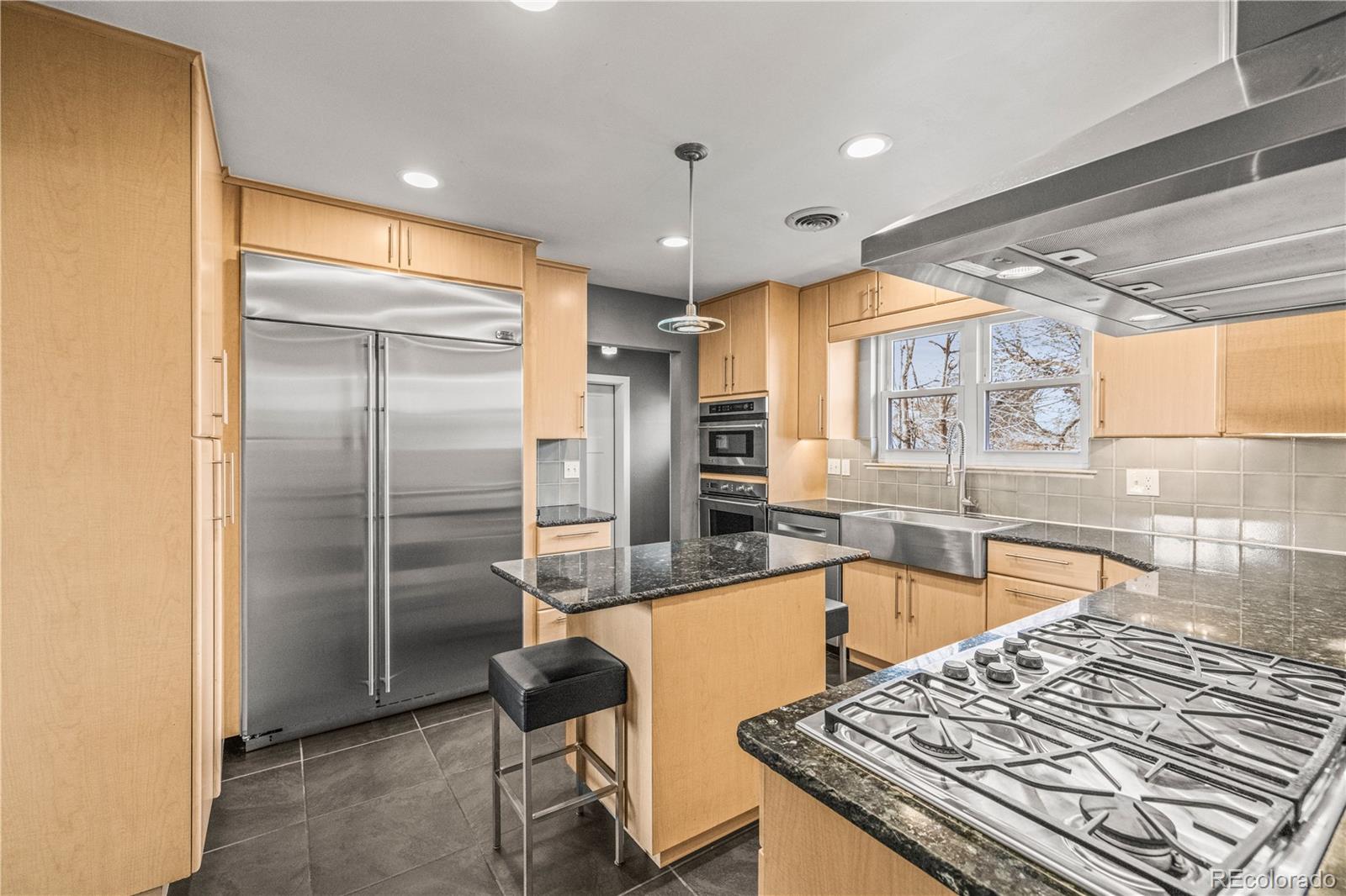 7005 West 44th Avenue Wheat Ridge, CO 80033 - Photo 11 of 37 a kitchen with stainless steel appliances granite countertop a sink and a refrigerator