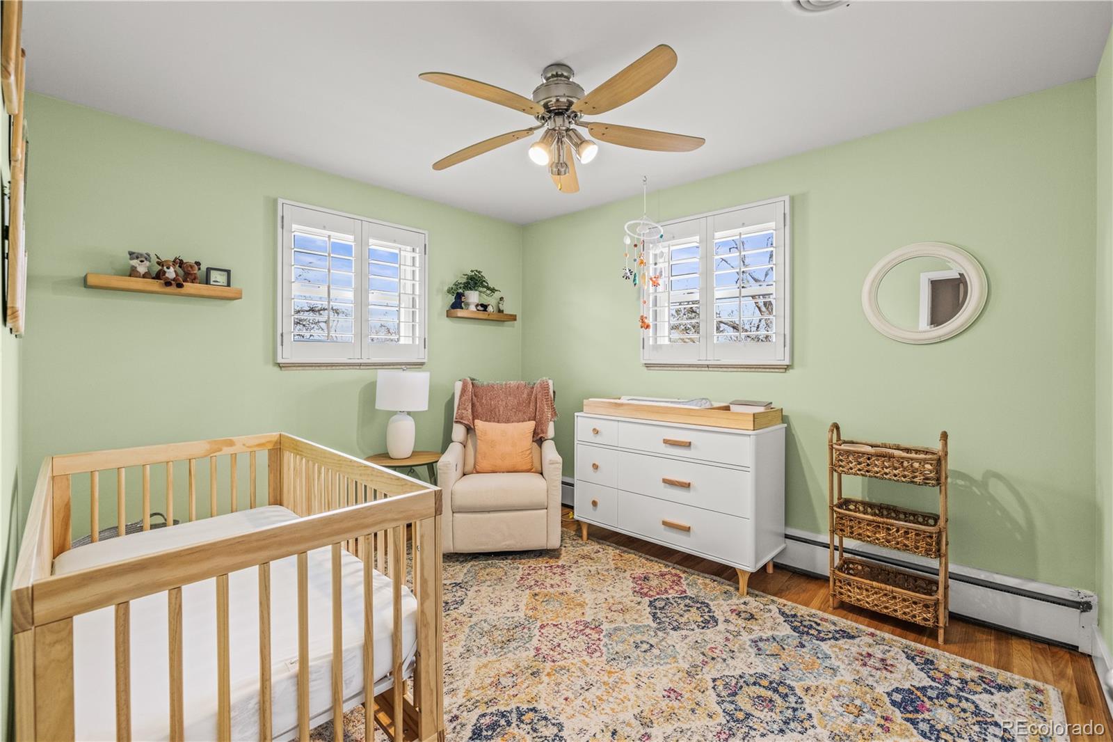 7005 West 44th Avenue Wheat Ridge, CO 80033 - Photo 20 of 37 a bedroom with a baby bed a chandelier and a dresser
