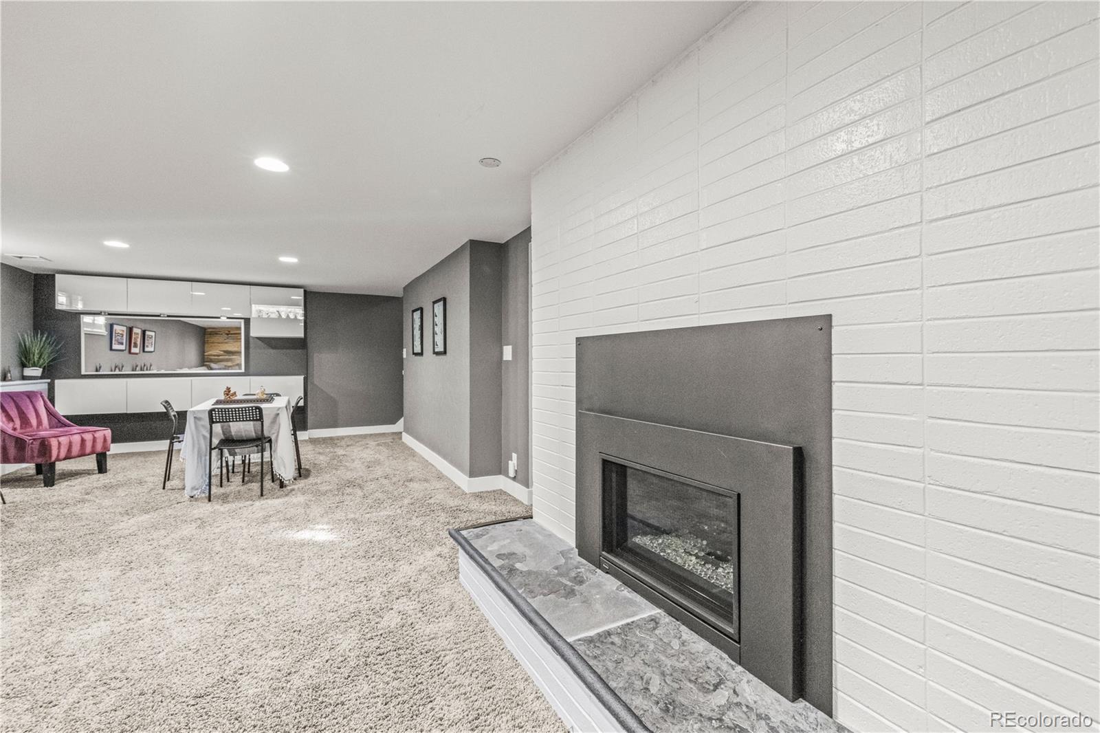 7005 West 44th Avenue Wheat Ridge, CO 80033 - Photo 25 of 37 a living room with furniture a fireplace and kitchen view