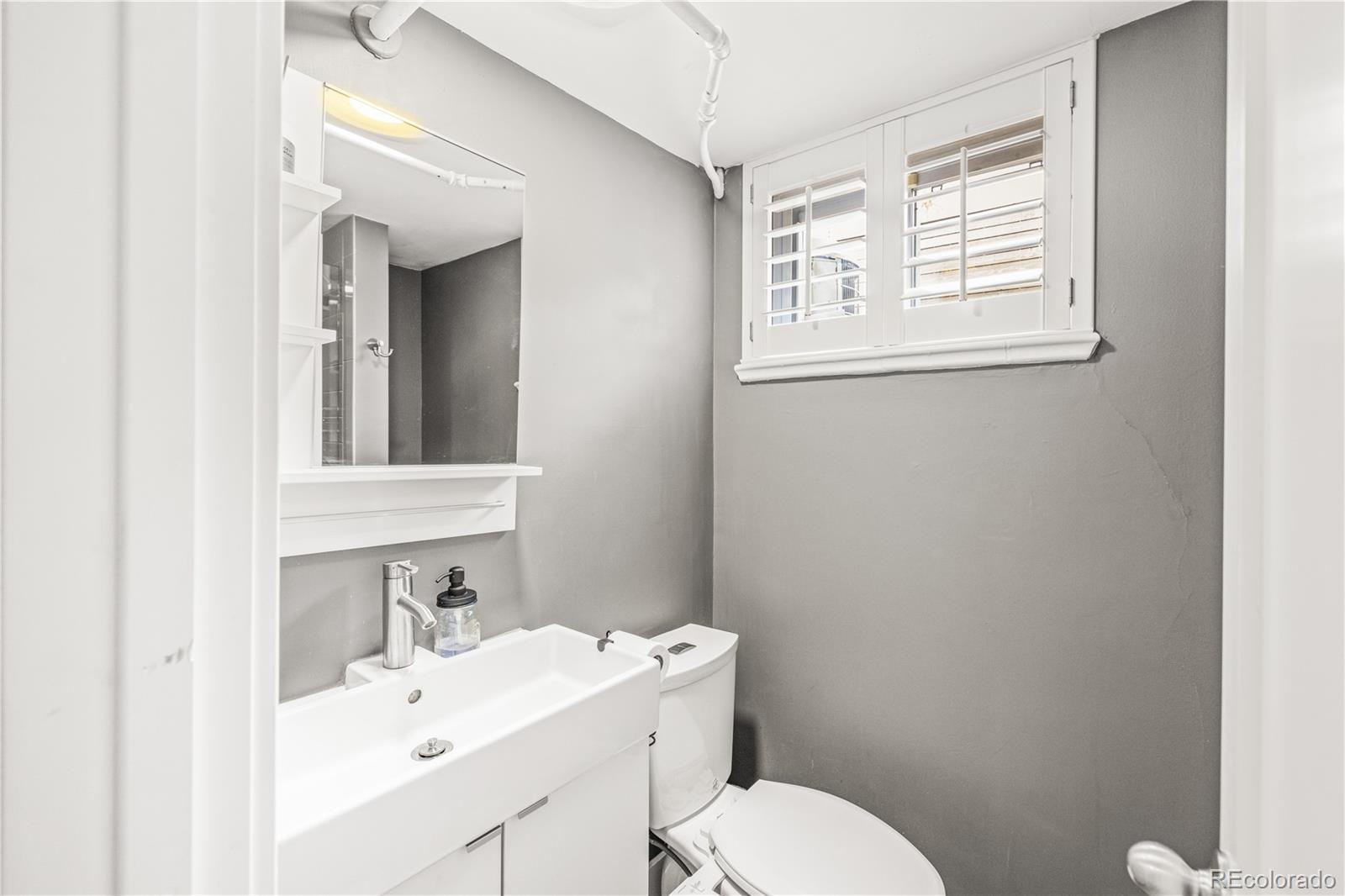 7005 West 44th Avenue Wheat Ridge, CO 80033 - Photo 31 of 37 a bathroom with a toilet sink vanity and mirror