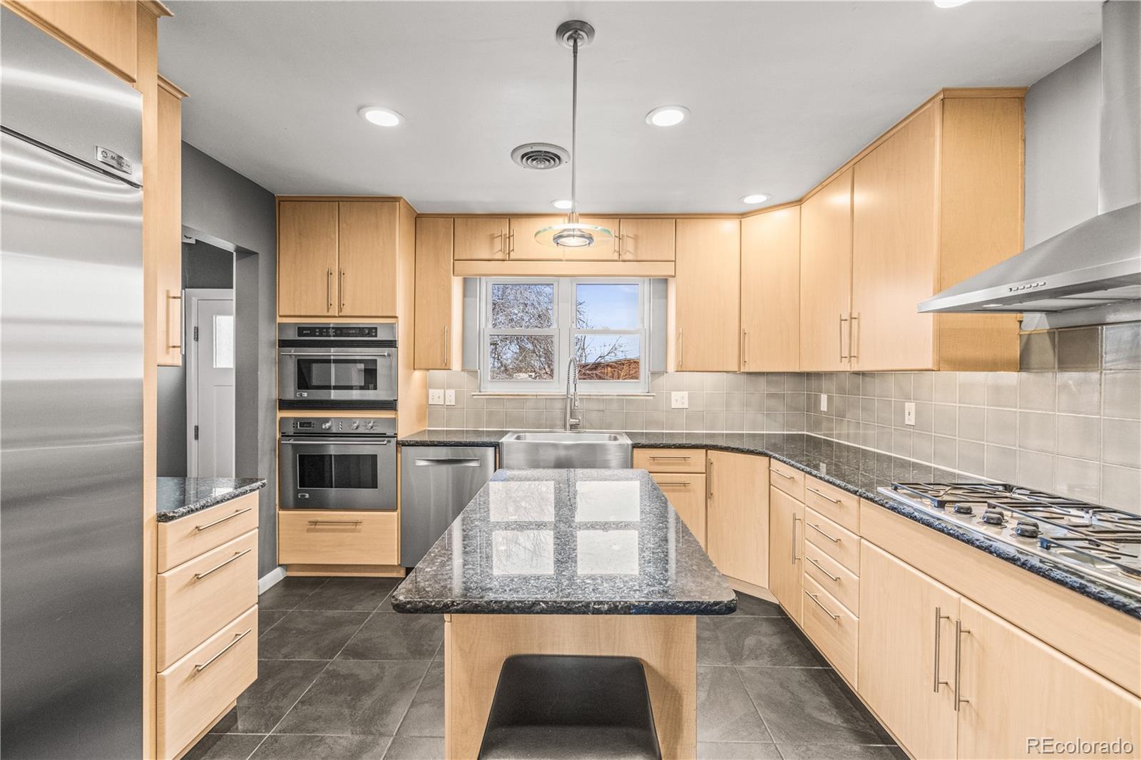 7005 West 44th Avenue Wheat Ridge, CO 80033 - Photo 4 of 37 a large kitchen with granite countertop a large counter top stainless steel appliances and cabinets