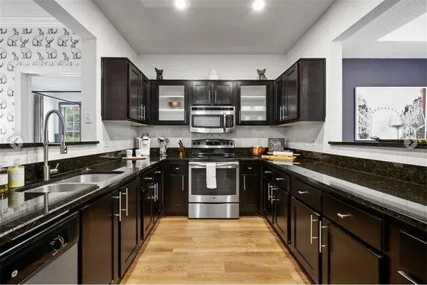 a kitchen with stainless steel appliances granite countertop a stove a sink and a microwave