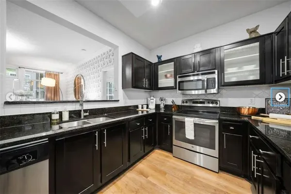 a kitchen with stainless steel appliances granite countertop a stove a sink dishwasher and a microwave oven with wooden cabinets