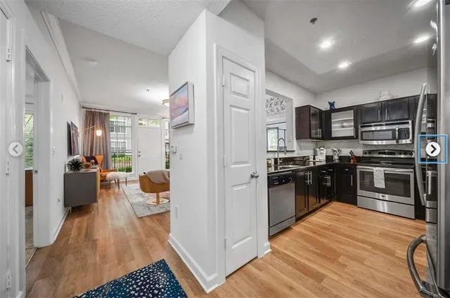 a kitchen with a refrigerator a stove top oven a sink dishwasher a dining table and chairs with wooden floor