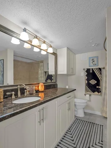 a bathroom with a granite countertop sink a toilet and a mirror