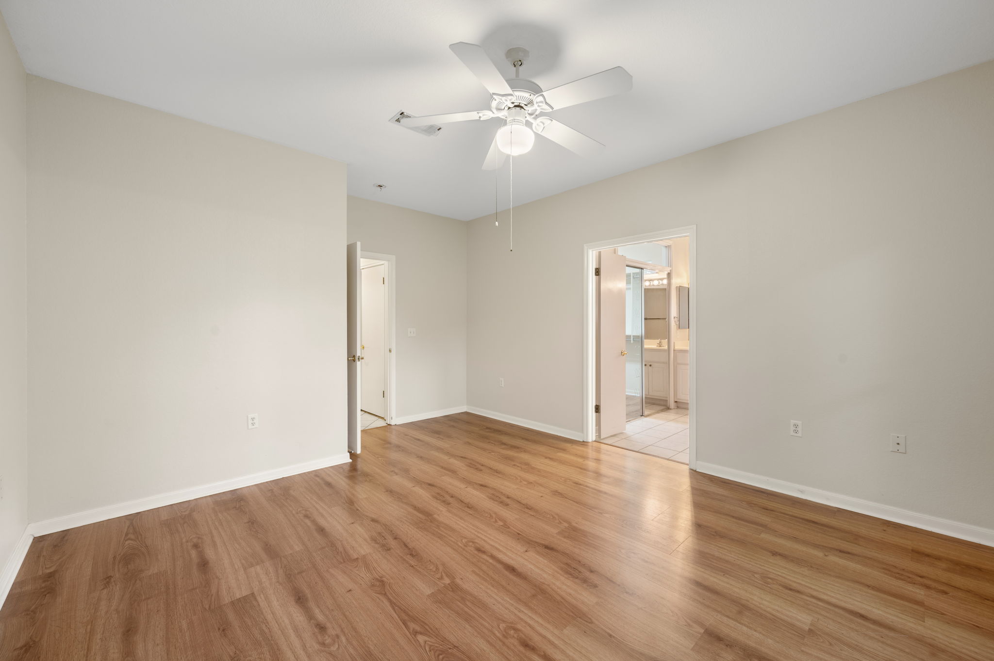 118 Bass Street Georgetown, TX 78633 - Photo 24 of 40 Laminate flooring extends into this spacious primary bedroom, offering seamless access to the en suite bathroom.