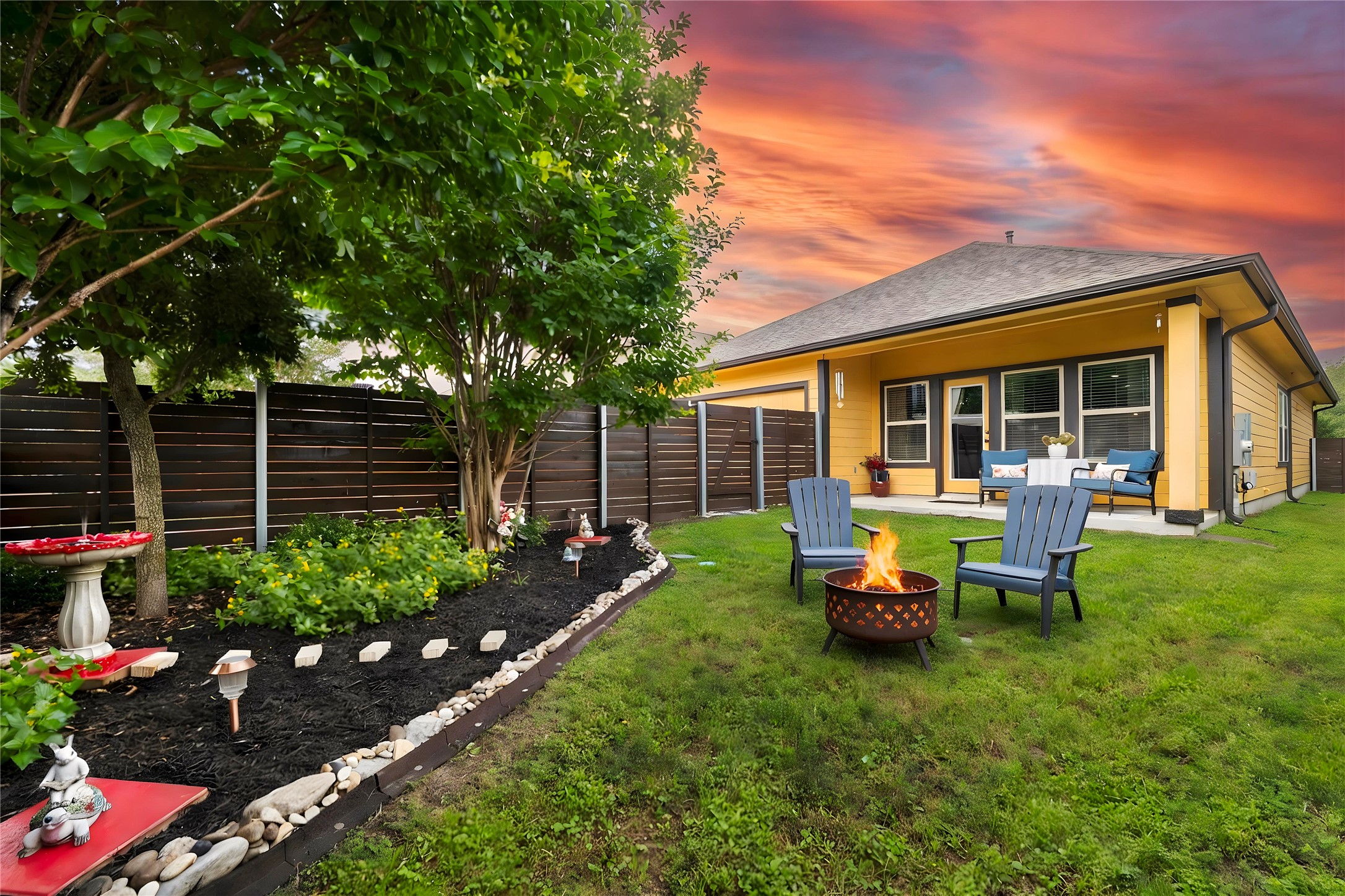 8721 Sikes Way Austin, TX 78747 - Photo 2 of 33 Virtually staged - Expansive backyard at dusk featuring a manicured lawn, established trees, and a decorative landscaped garden bed