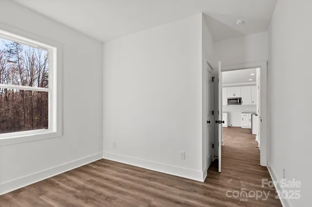 a view of a hallway with wooden floor and closet