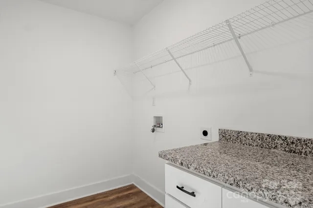 an empty room with wooden floor chandelier fan and windows
