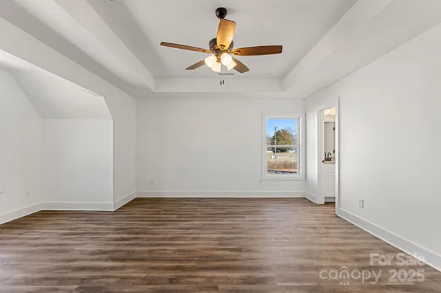 a view of an empty room with window and wooden floor