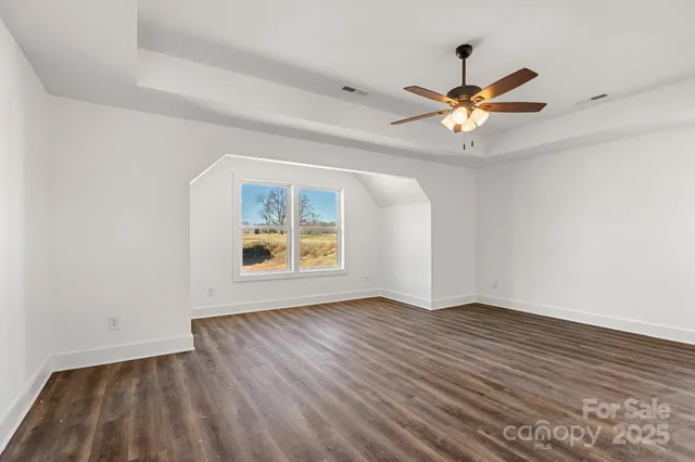 a view of an empty room with window and a chandelier fan