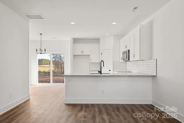 a kitchen with stainless steel appliances granite countertop a sink a stove and a wooden floors