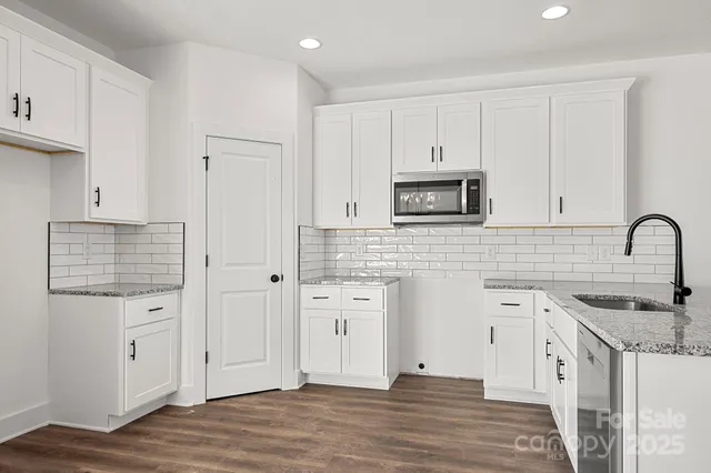 a kitchen with granite countertop white cabinets and stainless steel appliances
