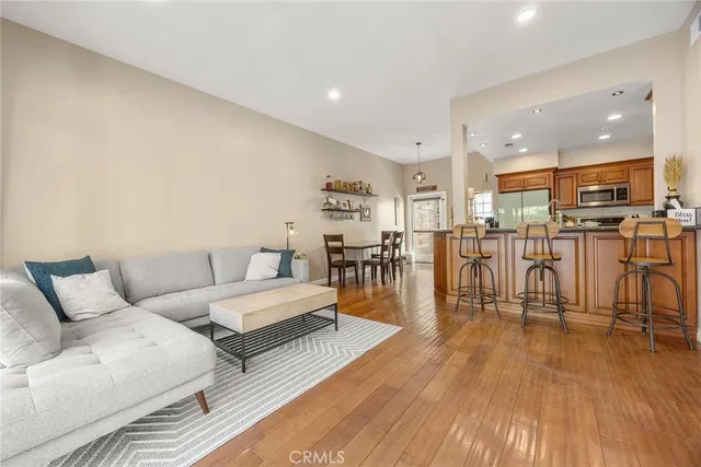 a living room with lots of furniture wooden floor and a kitchen view