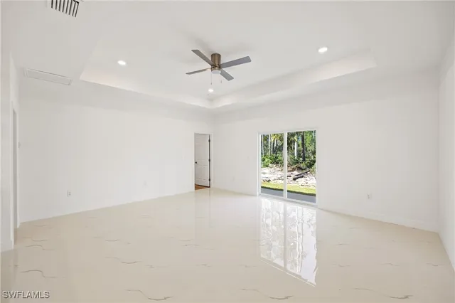 an empty room with windows and fan