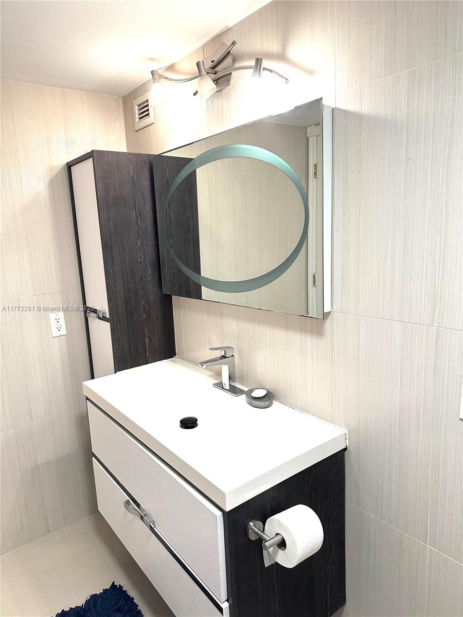 427 Golden Isles Drive, Unit 5G Hallandale Beach, FL 33009 - Photo 32 of 35 a bathroom with a sink vanity and a mirror