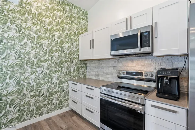a kitchen with granite countertop a refrigerator stove and microwave
