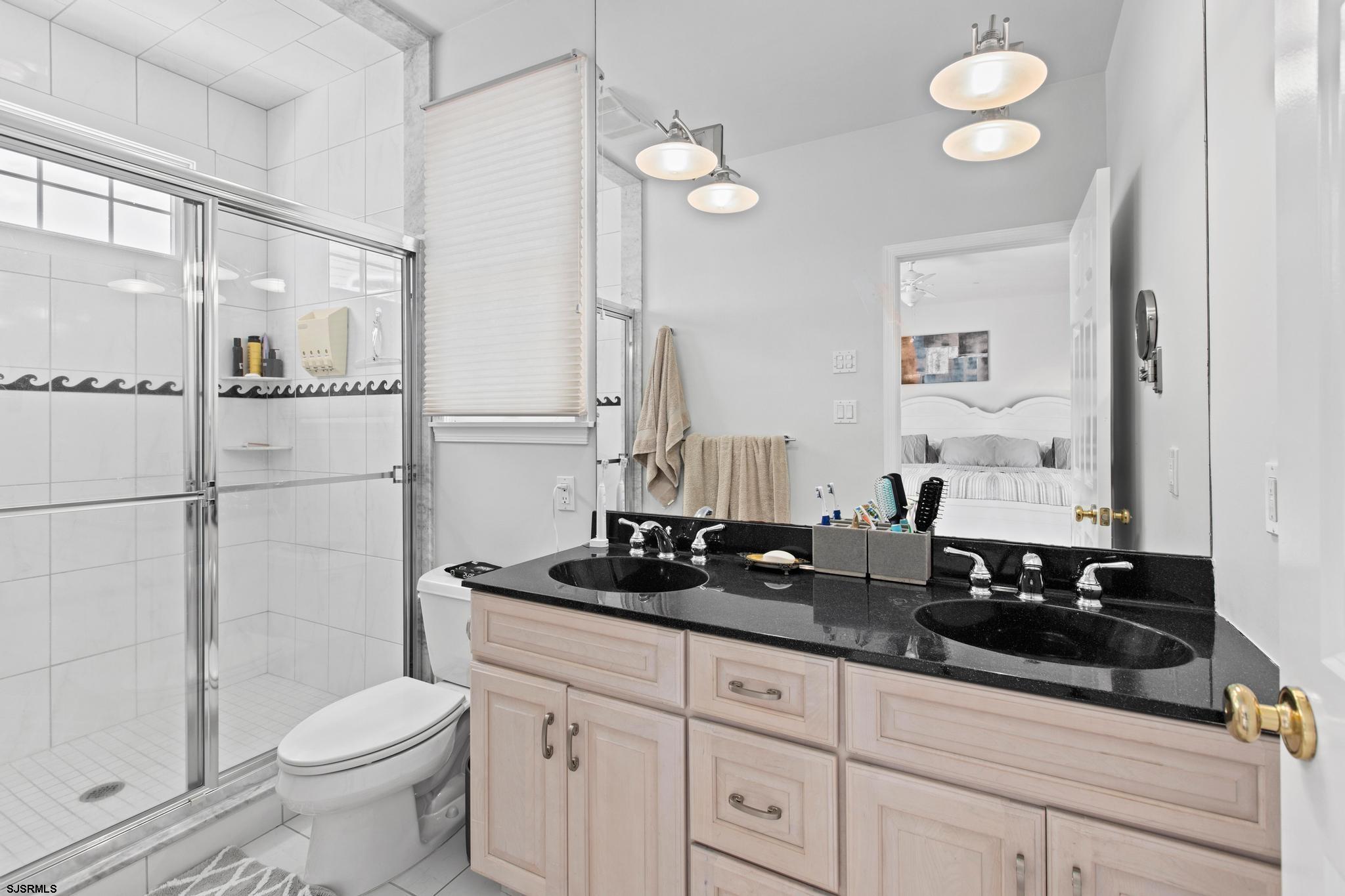 1 South Douglas Avenue, Unit 1 Margate City, NJ 08402 - Photo 29 of 48 a bathroom with a granite countertop sink a toilet a mirror and shower