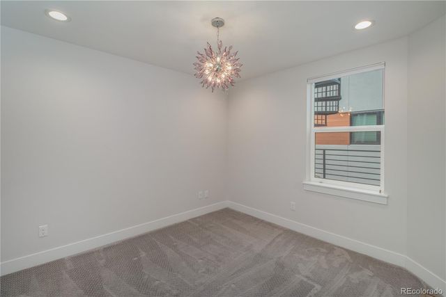 an empty room with windows and chandelier fan