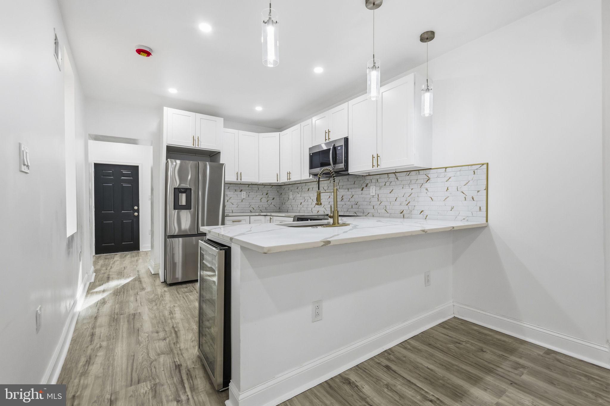 5542 Pemberton Street Philadelphia, PA 19143 - Photo 4 of 22 a kitchen with kitchen island a sink stainless steel appliances and cabinets