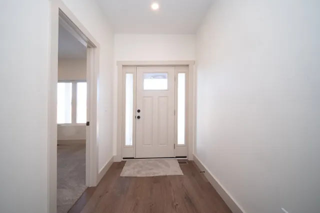 a view of a hallway with wooden floor and a bathroom
