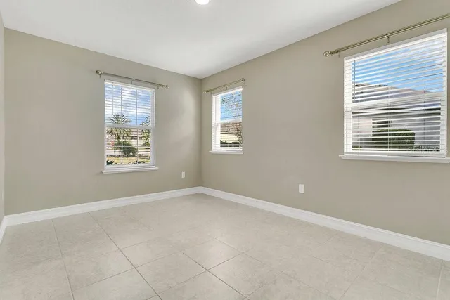 an empty room with kitchen and chandelier fan